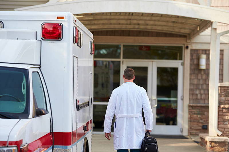 Выезд врача на дом Вид сзади на врача, идущего от скорой машины к дому
