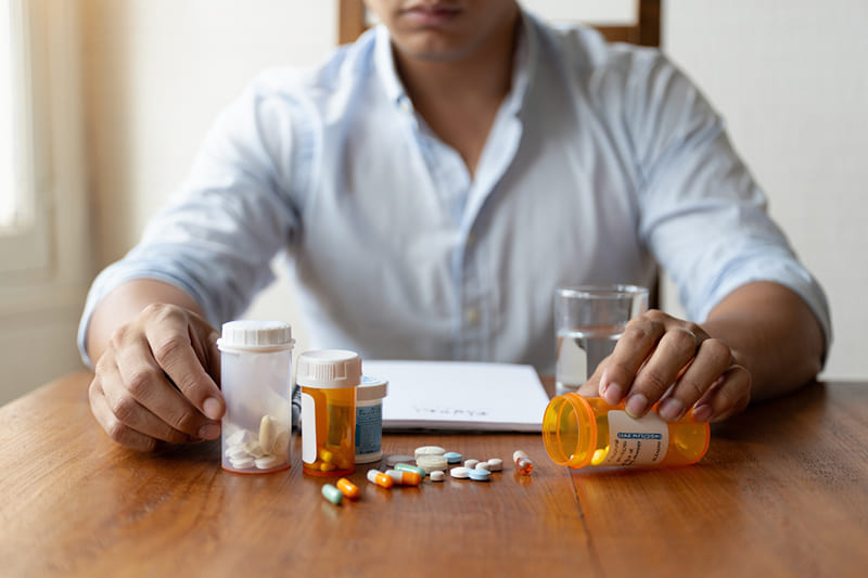 Медикаментозная терапия Человек рассматривает лекарства на столе