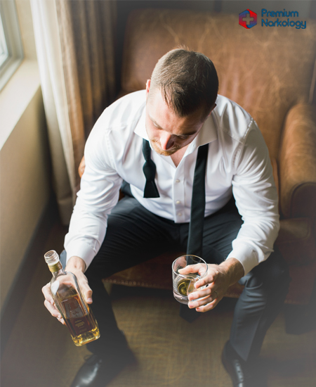 Мужчина сидит с алкоголем в руках