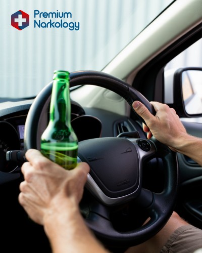 Мужчина сидит за рулем и держит алкоголь